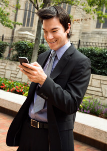 Businessman smiling at cell phone message.